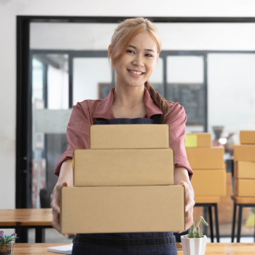 e-commerce business owner holds 3 boxes to be shipped.